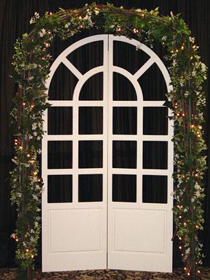 Garden Arbor surrounds a French Door with lights and ivy This