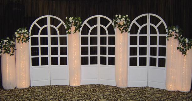 French Doors backdrop accented with lighted columns and greenery create an