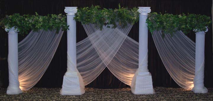 Round grecian columns with greenery bars and sweeping chiffon add a